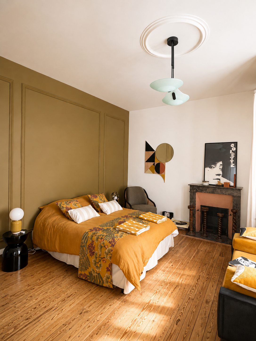 La chambre moderniste de la Villa Folie : lit double ocre, boiseries olive et cheminée d'époque