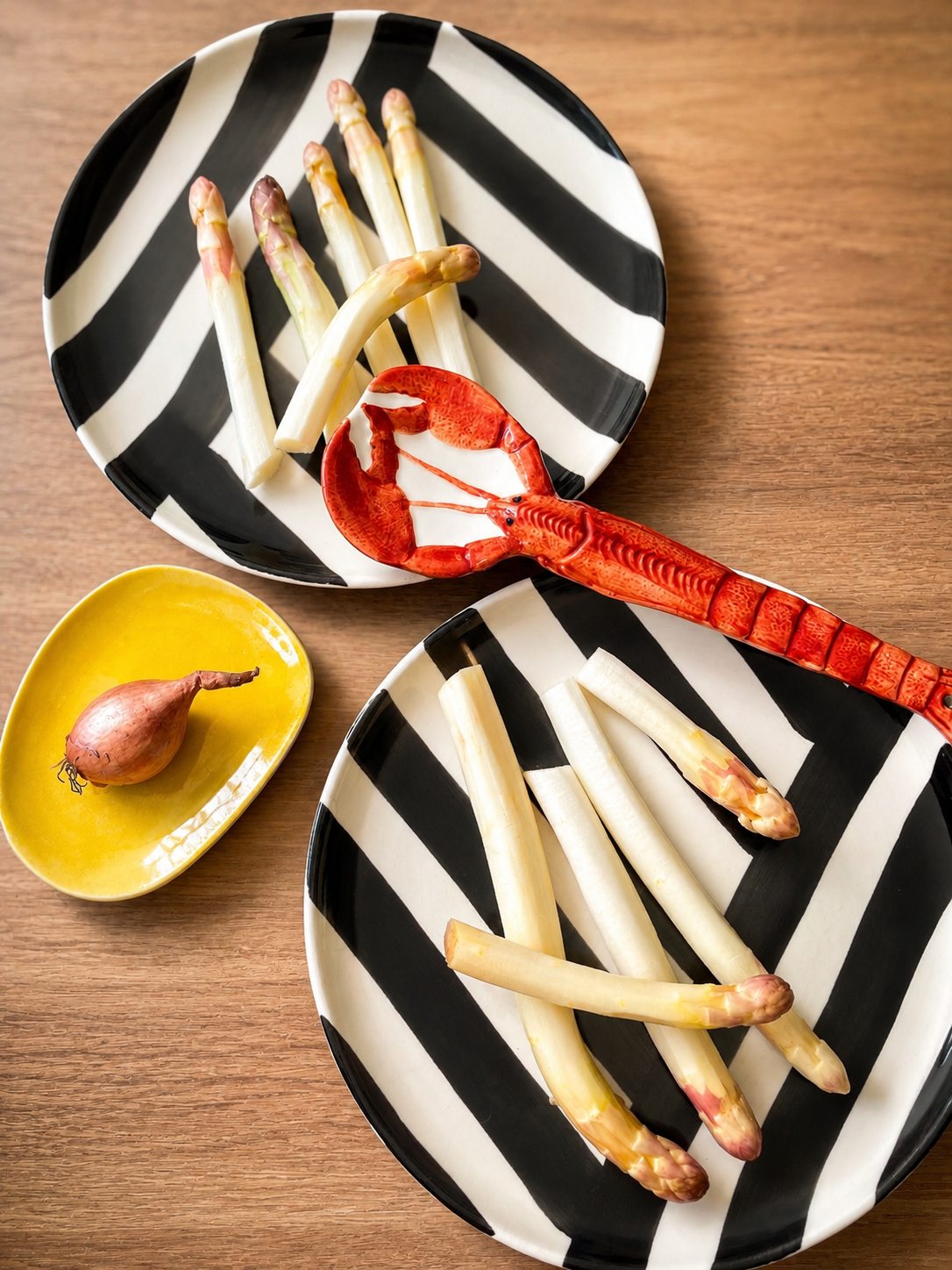 Asperges blanches servies dans des assiettes rayées noir et blanc