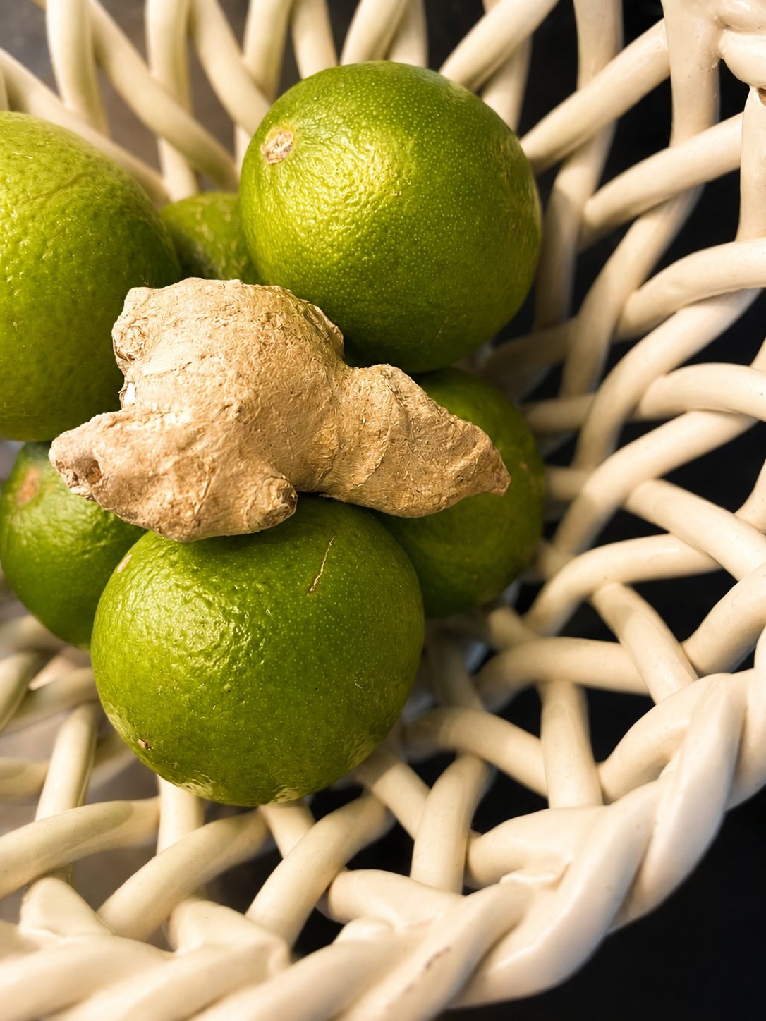 Citrons verts et gingembre dans une corbeille en céramique tressée