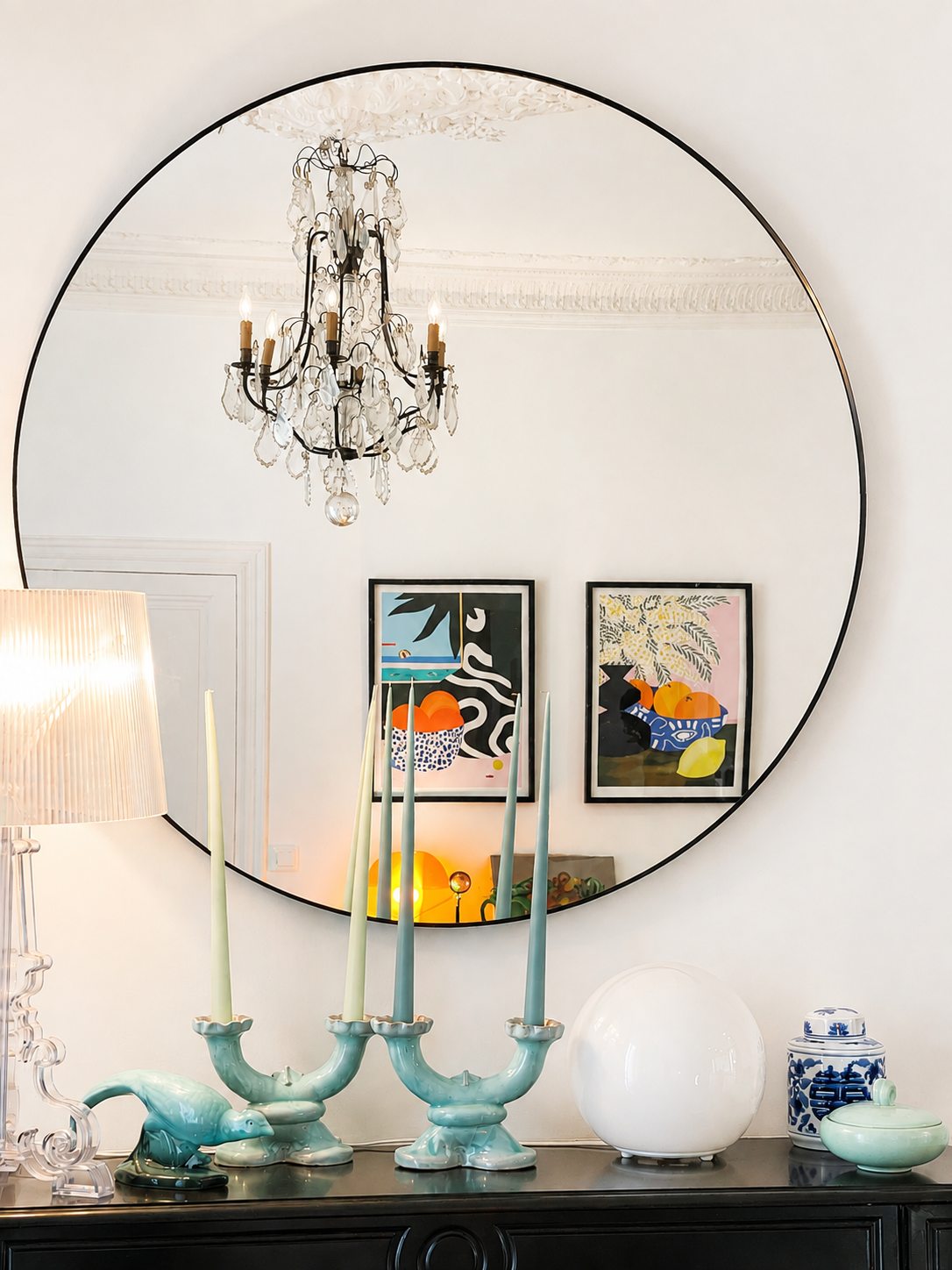 Grand miroir rond réfléchissant le lustre et les œuvres de la Villa Folie