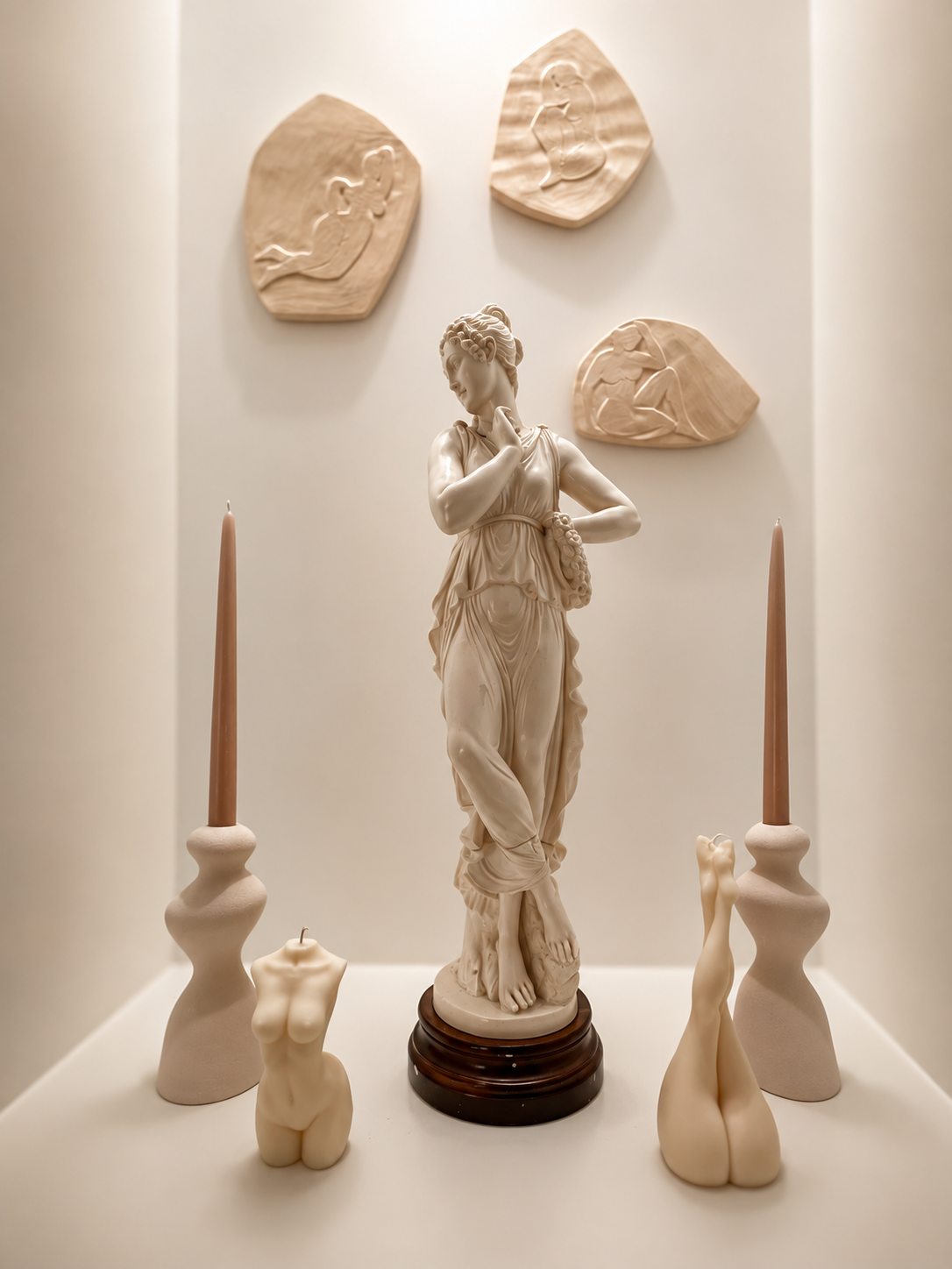 Statuette et sculptures en céramique blanche entre deux bougies