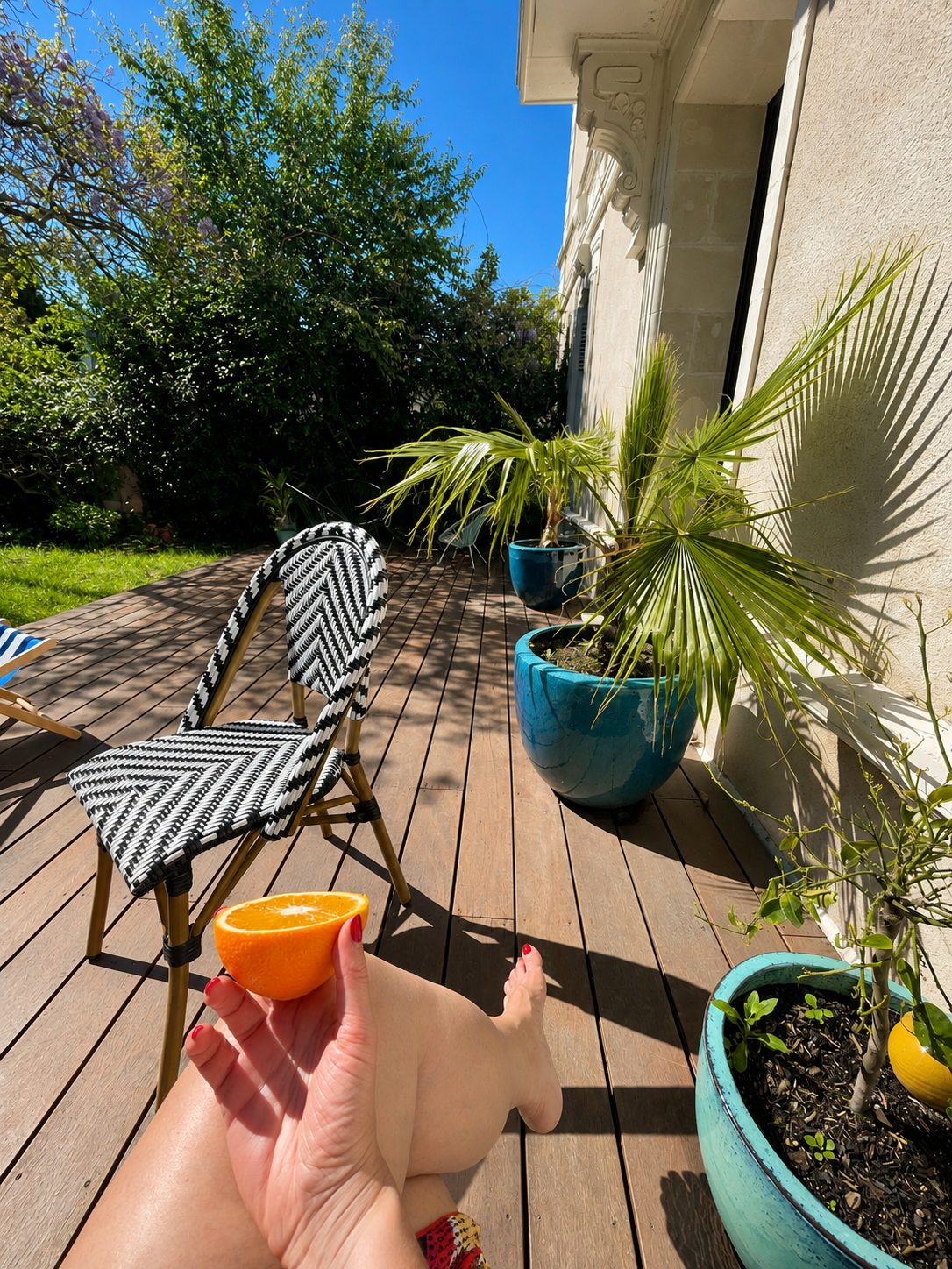 Chaise bistrot et palmier en pot sur la terrasse en bois de la Villa Folie