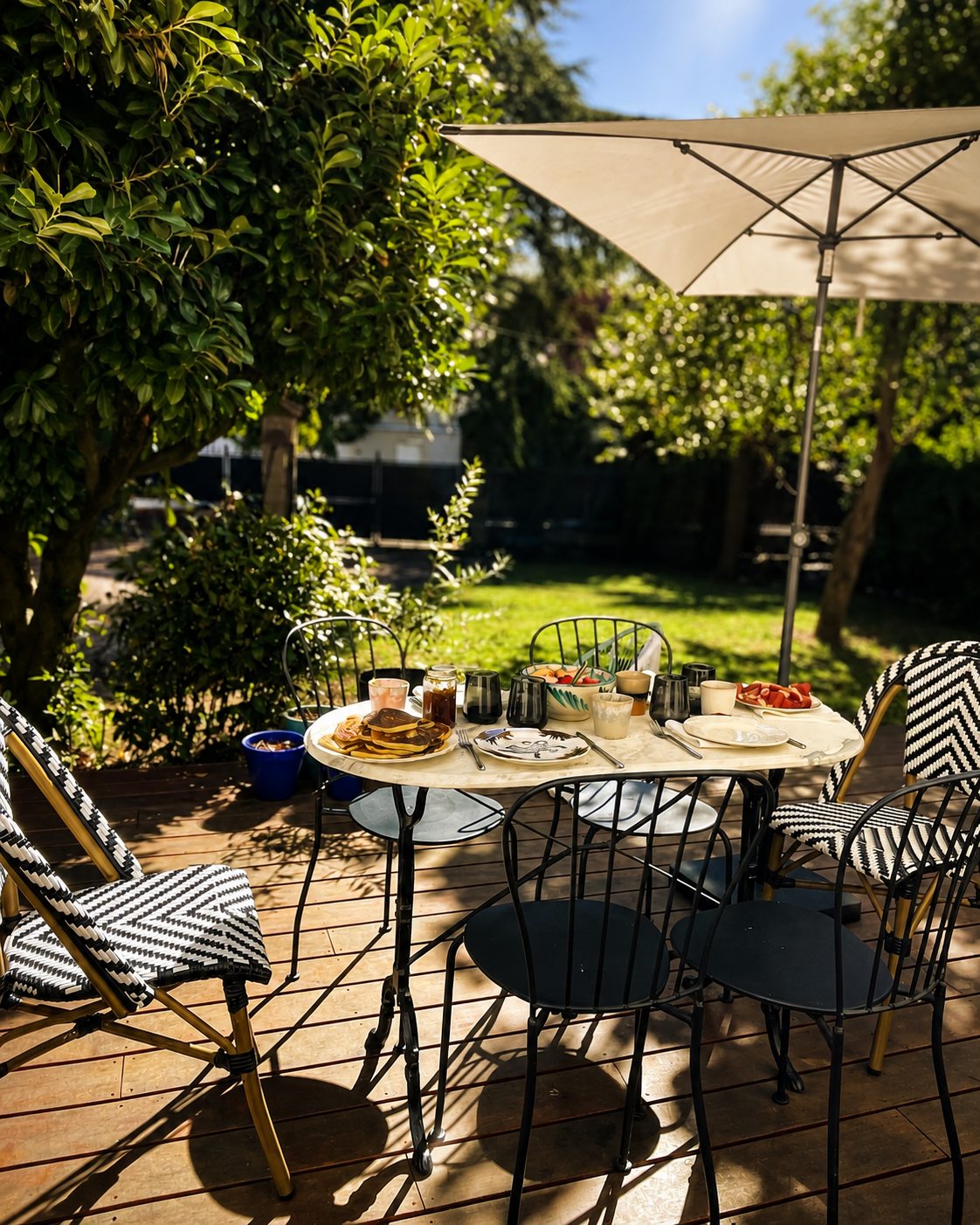 Grande table dressée sous le parasol dans le jardin de la Villa Folie, pour un déjeuner à six