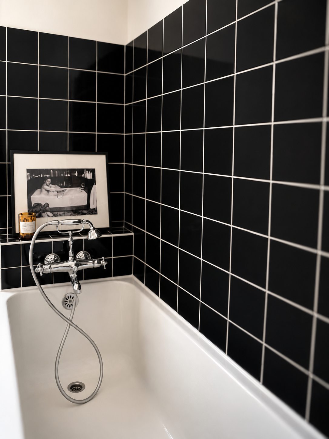 La baignoire, le carrelage noir et une photographie en noir et blanc