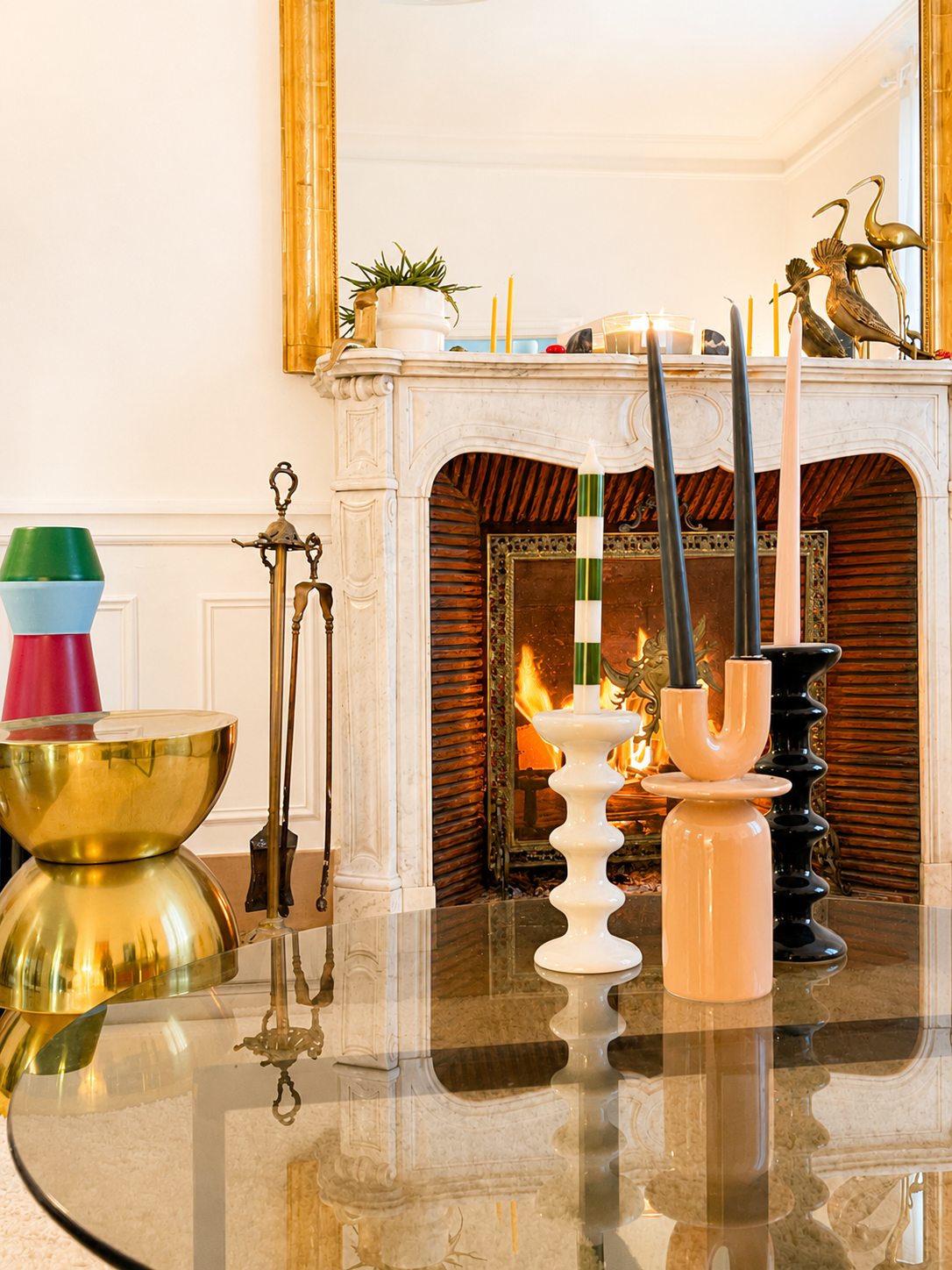 Le feu dans la cheminée du salon de la Villa Folie, bougies sculpturales et table basse en verre